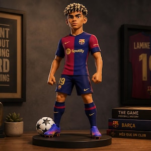Op de afbeelding: Een gestileerd figuurtje van een voetballer met krullend haar, gekleed in een blauw en rood FC Barcelona-shirt met nummer 19, bijpassende broek en blauwe sokken. Het figuurtje staat op een ronde voet naast een voetbal tegen een donkere achtergrond.