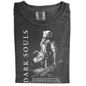 May include: Dark grey t-shirt featuring a detailed white illustration of a knight in armor, holding a sword and shield. The words "DARK SOULS" are printed vertically on the left side. Below the knight is a quote from the game.