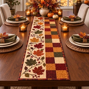May include: A rectangular table runner featuring a split design with one side displaying a quilted pattern of autumn leaves and berries on a cream background, and the other side showcasing a checkered pattern in shades of red, orange, and green.