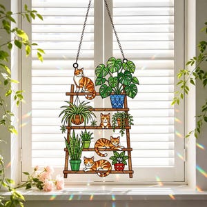 Puede incluir: Un atrapasoles de vidrieras que presenta una estantería de escalera de madera marrón con cuatro niveles. La estantería sostiene tres gatos atigrados naranjas y varias plantas verdes en macetas, incluyendo una monstera en una maceta azul, una cinta y una sansevieria.