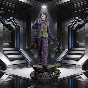 May include: A detailed statue of the Joker, a DC Comics villain, in a purple suit and coat, holding a gun. The figure stands on a rocky base with a clown face and the word "SERIOUS" visible. The background is a futuristic, metallic environment.