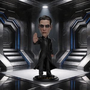 Puede incluir: Figura de bobblehead de un hombre con abrigo negro largo y gafas de sol, con la mano derecha levantada en señal de stop. La figura está sobre una base negra, sobre un fondo futurista y metálico.