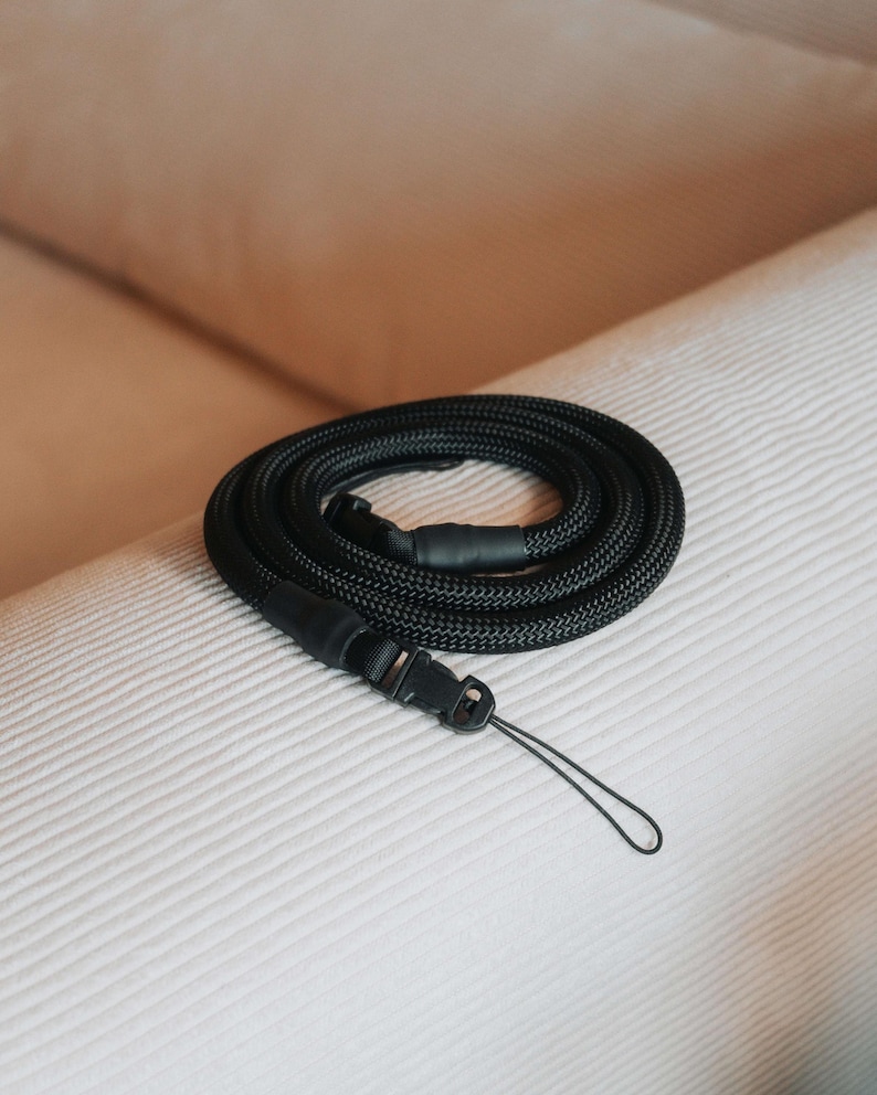 Pu&ograve; includere: Un cordino nero arrotolato, con una trama intrecciata, dotato di un fermaglio in plastica e un piccolo anello. Il cordino &egrave; progettato per essere indossato al collo o al polso, adatto per chiavi, un telefono o un badge.