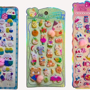 以下が含まれることがあります： カラフルな漫画の動物デザインが特徴の3枚のステッカーシート。ステッカーには、ひよこ、ウサギ、クマなどの様々なキャラクター、食べ物、装飾要素が含まれています。シートには「PAW Stickers」と「Cute Animals」という文字が書かれています。