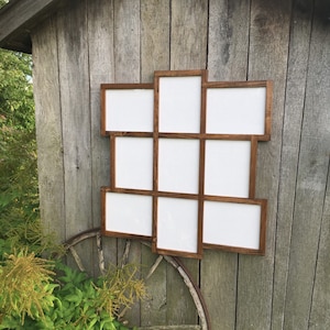 May include: A rustic wooden picture frame with nine openings, arranged in a unique geometric pattern. The frame is stained a dark brown color and has a distressed finish.