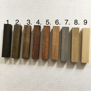 May include: Nine wood samples stained in different colors, numbered 1 through 9. The colors range from dark brown to light brown, gray, and natural wood.