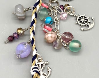 Dije de cuentas para bolso hecho a mano. Accesorio de estilo bohemio. Cuentas de vidrio moradas, verde azulado y rosas con dijes náuticos. Cierre de plata antigua.