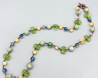 Collar de cuentas de crochet. Verde, espuma de mar, azul y crema, sobre cordón de nailon marrón dorado. Joyería de crochet de primavera.