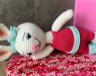 Muñeca de conejito de ganchillo con mejillas sonrojadas y atuendo rosa.