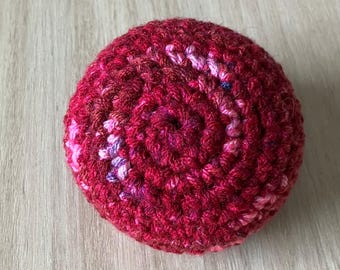 Pelota de ganchillo para hacky sack en combinación de colores rojo y granate jaspeado.