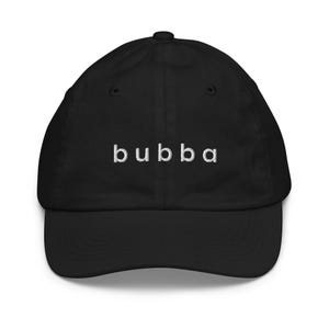 Könnte beinhalten: Schwarze Baseballkappe mit dem Wort "bubba" in Weiß gestickt. Die Kappe hat einen gebogenen Schirm und eine runde Krone. Ein klassisches, lässiges Accessoire.