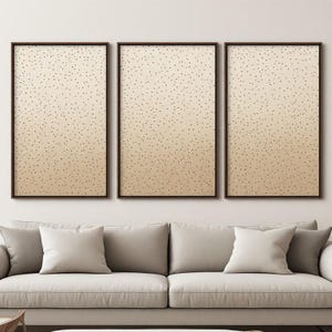 Peut inclure: Un ensemble de trois tableaux muraux rectangulaires dans des cadres marron foncé. Chaque pièce présente un fond dégradé allant du beige clair au beige doré, recouvert d'un motif dense de petits points marron foncé, créant un effet moucheté.