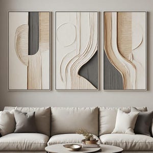 Può includere: Un set di tre pannelli artistici rettangolari da parete con disegni in gesso testurizzato in rilievo nei toni del crema, beige e grigio antracite. L'opera presenta forme geometriche astratte, linee curve e scanalature verticali su una superficie piana.
