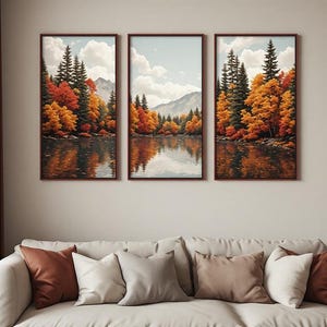 Peut inclure: Un ensemble de trois tableaux muraux verticaux encadrés représentant un paysage. La scène montre un lac calme reflétant une forêt aux feuillages d'automne dans des tons orange, rouge et jaune, avec des montagnes en arrière-plan.