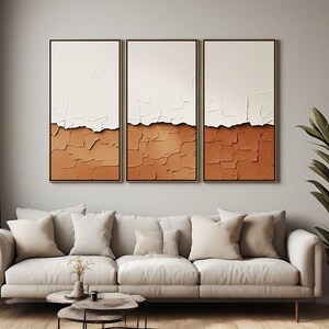 Peut inclure: Un ensemble de trois tableaux muraux en triptyque composé de toiles rectangulaires verticales avec une finition empâtée épaisse et texturée. Chaque toile présente un design divisé horizontalement avec une partie supérieure blanche lisse.