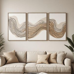 May include: A set of three rectangular wall art prints featuring abstract wavy line patterns in shades of beige, tan, and dark brown on a white background, each enclosed in a thin, light-colored wooden frame and displayed in a horizontal row.