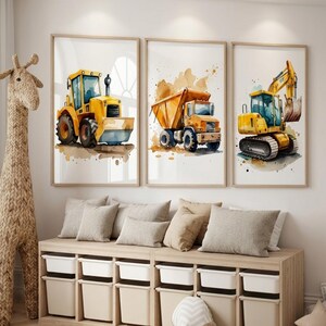 Peut inclure: Trois impressions encadrées à l'aquarelle représentant des engins de chantier : une chargeuse frontale jaune, un camion benne et une excavatrice. Les impressions ont un fond neutre avec des éclaboussures de peinture marron et orange. Les cadres sont marron clair.
