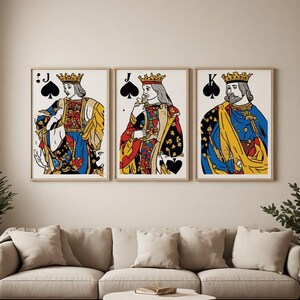 Peut inclure: Trois impressions d'art mural encadrées représentant des illustrations de cartes à jouer stylisées. L'impression de gauche montre un Valet de pique, celle du centre un Valet de pique et celle de droite un Roi de pique, en bleu, jaune et rouge.