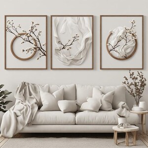 Peut inclure: Un ensemble de trois cadres muraux représentant des branches de cerisier en fleurs blanches et du tissu blanc drapé. Deux cadres intègrent un élément circulaire en bois, tandis que celui du centre montre du tissu blanc fluide.
