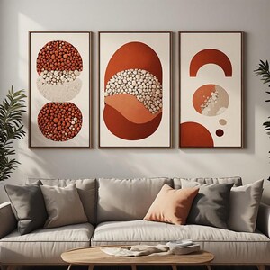 Peut inclure: Un ensemble de trois tableaux encadrés présentant des formes géométriques abstraites dans des tons terre cuite, orange brûlé et crème. Les motifs intègrent des textures de galets et des blocs de couleur unie dans des cadres rectangulaires.