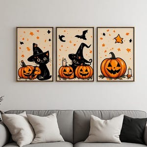 Op de afbeelding: Een set van drie ingelijste wandkunstwerken met Halloween-thema's. De illustraties tonen zwarte katten met puntige heksenhoeden, oranje pompoenen, brandende kaarsen, een vliegende vleermuis, een ster en verspreide oranje bladvormen.