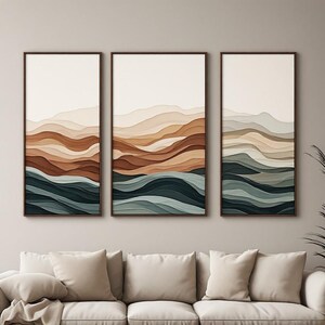 Puede incluir: Un conjunto de arte mural tríptico que consta de tres lienzos rectangulares verticales. Cada lienzo muestra un diseño de paisaje en capas con líneas horizontales onduladas en tonos crema, beige, terracota, marrón oscuro, verde salvia y azul cerceta.