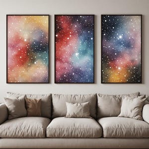 Peut inclure: Un ensemble de trois impressions d'art mural rectangulaires présentant un motif de nébuleuse galactique vibrante avec des nuages tourbillonnants de teintes rouges, jaunes, bleues et violettes, parsemés de nombreux points blancs étoilés.
