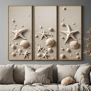 Peut inclure: Un ensemble de trois tableaux muraux verticaux sur fond beige clair. Chaque panneau présente une collection d'étoiles de mer blanches et de divers coquillages beiges et blancs dispersés sur la surface, encadrés par de fines bordures dorées.