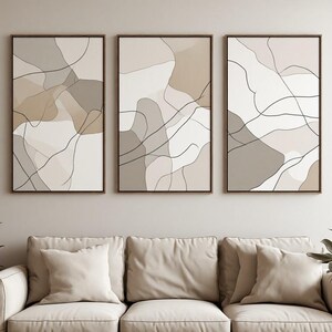 Peut inclure: Un ensemble de trois impressions d'art mural rectangulaires verticales présentant des compositions abstraites de formes organiques superposées dans des tons beige, crème et taupe, accentuées par de fines lignes noires fluides, encadrées de bois.