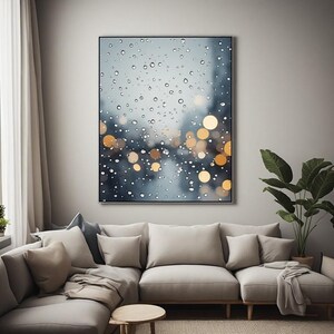 Peut inclure: Une impression murale rectangulaire représentant un gros plan de gouttes de pluie sur une surface vitrée. L'arrière-plan montre un paysage urbain flou avec des cercles de lumière bokeh dorés et doux sur un fond bleu et gris.
