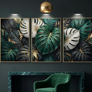 Peut inclure: Trois tableaux encadrés représentant des feuilles de monstera stylisées. Les feuilles sont de couleur verte, blanche et noire, avec des détails dorés. L'œuvre est placée sur un fond sombre, créant un contraste saisissant.