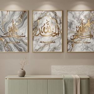 Peut inclure: Trois œuvres d'art murales encadrées avec de la calligraphie dorée sur un fond en marbre. La calligraphie est en script arabe, avec les mots "Subhan Allah", "Al Hamdu Lillah" et "Allahu Akbar". Les cadres sont dorés.