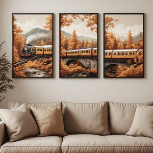 May include: A triptych wall art set featuring a steam train travelling through an autumn forest landscape. The yellow passenger cars move across a stone bridge over a river, surrounded by orange and gold trees with mountains in the background.