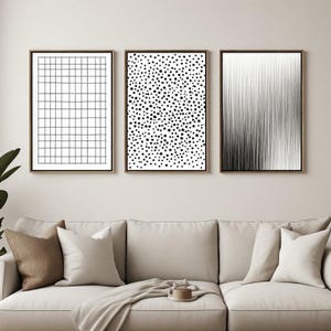 May include: A set of three rectangular wall art prints in thin wooden frames. The left print features a black grid pattern on a white background, the center print displays black polka dots, and the right print shows vertical black lines.