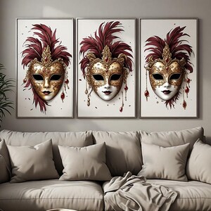 Könnte beinhalten: Ein Triptychon aus drei gerahmten Wandbildern, die jeweils eine detaillierte Illustration einer goldenen venezianischen Maske mit dunkelroten Federn und hängenden roten Edelsteinakzenten auf weißem Grund zeigen.