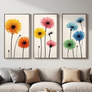Peut inclure: Un ensemble de trois cadres muraux verticaux présentant des illustrations florales sur fond crème. Les impressions affichent des fleurs aux pétales colorés en jaune, orange, rose, bleu et vert, portées par de fines tiges noires.