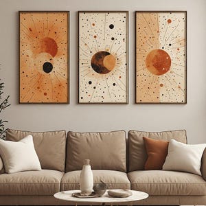 Peut inclure: Un ensemble de trois cadres muraux rectangulaires représentant des motifs célestes dans des tons orange, crème et noir. Chaque impression présente un élément central circulaire de soleil ou de lune entouré de lignes rayonnantes.