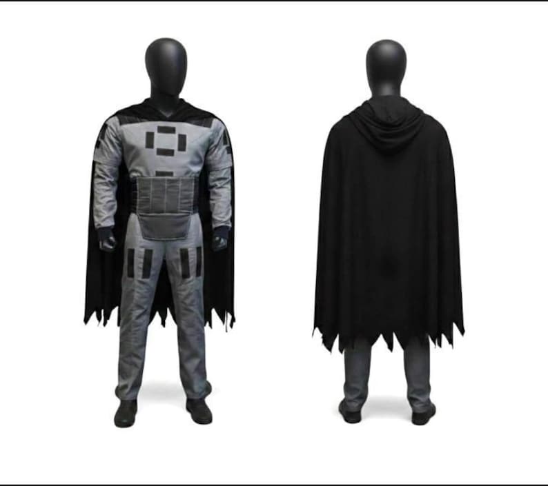 May include: A costume set consisting of a gray long-sleeved top and matching pants featuring black rectangular accents on the chest, shoulders, and thighs. A black hooded cape with a jagged hemline is worn over the outfit, which is displayed on a mannequin.