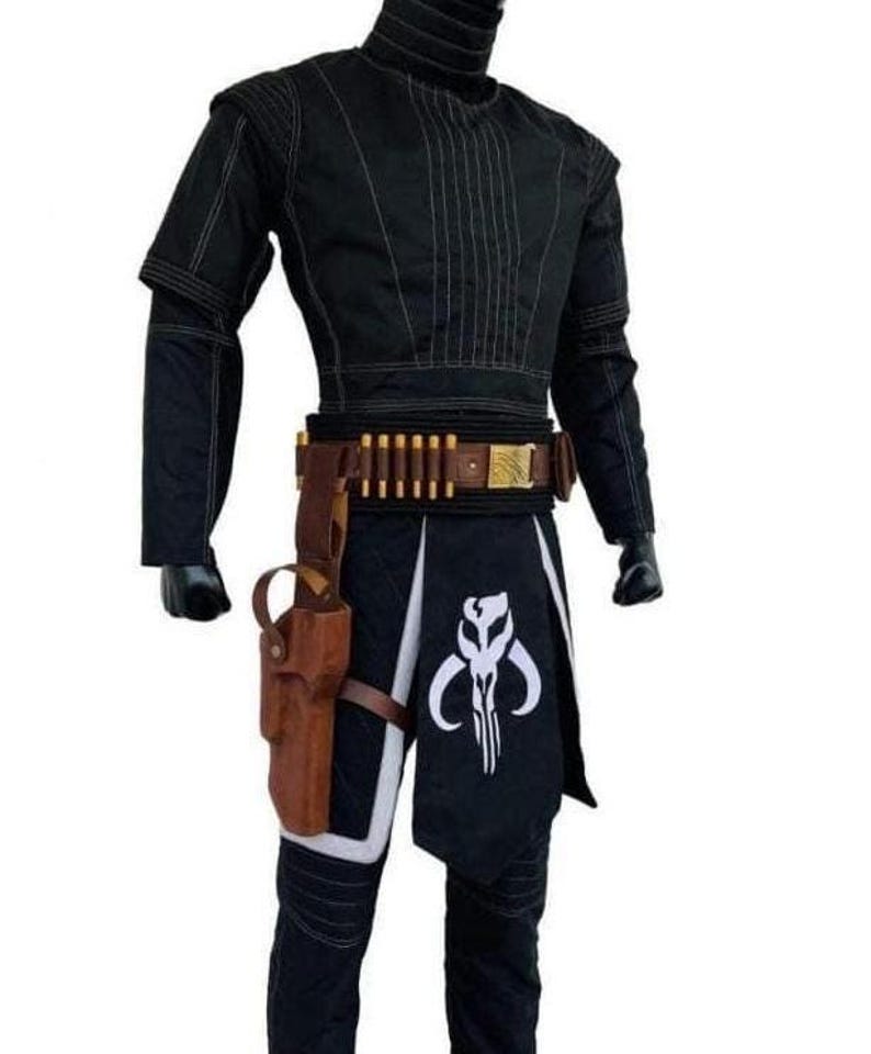 May include: A black long-sleeved shirt with vertical stitching, paired with black trousers featuring a white skull emblem. A brown leather utility belt with gold-colored ammunition loops and a holster is worn around the waist over the trousers.