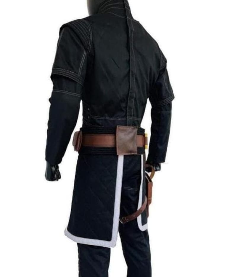 May include: A black long-sleeved jacket with visible stitching, paired with a brown leather utility belt featuring pouches. The outfit includes a black quilted skirt-like panel with a white border, worn over black trousers with a brown holster strap.