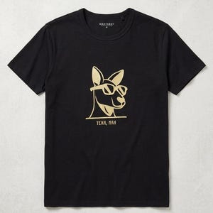 Peut inclure: T-shirt noir avec un motif doré de kangourou portant des lunettes de soleil. Le texte "YEAH, NAH" est en dessous. Le t-shirt a un col rond et des manches courtes. La marque "MANTARAY" est imprimée en haut du dos.