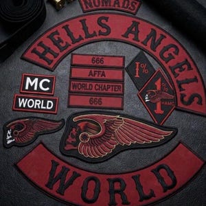 May include: A collection of embroidered patches featuring the text Hells Angels, World, MC, AFFA, 666, and World Chapter. The patches are red and black, including a diamond-shaped 1% patch and two winged skull emblems with detailed red and black stitching.