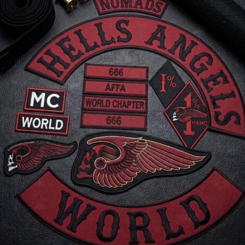 May include: A collection of embroidered patches featuring the text Hells Angels, World, MC, AFFA, 666, and World Chapter. The patches are red and black, including a diamond-shaped 1% patch and two winged skull emblems with detailed red and black stitching.