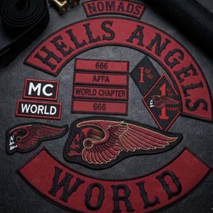May include: A collection of embroidered patches featuring red and black color schemes. The patches include text such as HELLS ANGELS, NOMADS, WORLD, MC, 666, AFFA, and WORLD CHAPTER, alongside a diamond-shaped 1% patch and winged skull emblems.