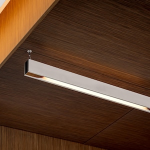 May include: A close-up of a modern, rectangular light fixture with a white, frosted diffuser. The light fixture is mounted to a brown wood ceiling.