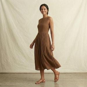K&ouml;nnte beinhalten: Ein &auml;rmelloses Midikleid in einfarbigem Braun mit strukturiertem Stoff, einem eng anliegenden Oberteil und einem gerafften, flie&szlig;enden Rock, der unter die Knie reicht. Das Kleid wird mit braunen Riemchensandalen mit Schnallenverschluss kombiniert.