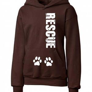 May include: Brown hooded sweatshirt with the word "RESCUE" printed vertically down the front in white. Two white paw prints are printed below the word.