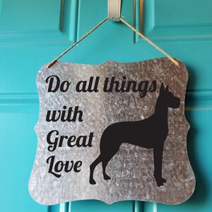 May include: A silver metal sign with a black silhouette of a dog and the text "Do all things with Great Love".