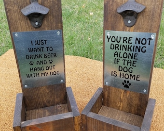 May include: Two wooden bottle openers with metal signs. The sign on the left says "I just want to drink beer and hang out with my dog". The sign on the right says "You're not drinking alone if the dog is home".