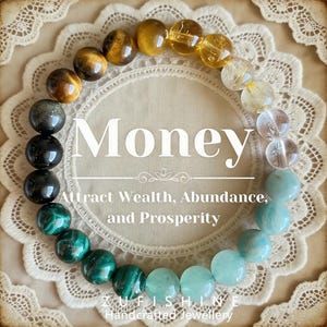 May include: A beaded bracelet with a variety of gemstones in shades of brown, yellow, green, and blue. The word "Money" is displayed in large white letters, with the text "Attract Wealth, Abundance, and Prosperity" below. The bracelet is on a white lace doily.